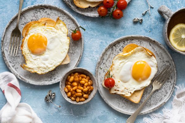 Fried eggs on toast with baked beans and cherry tomatoes.